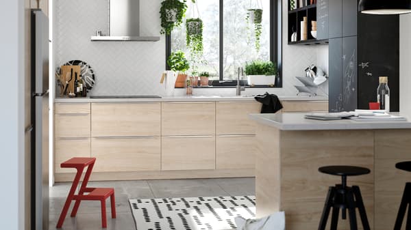 Armoires de cuisine avec portes ASKERSUND à effet frêne clair et armoires avec portes et revêtement anthracite pouvant être utilisées comme tableaux noirs.