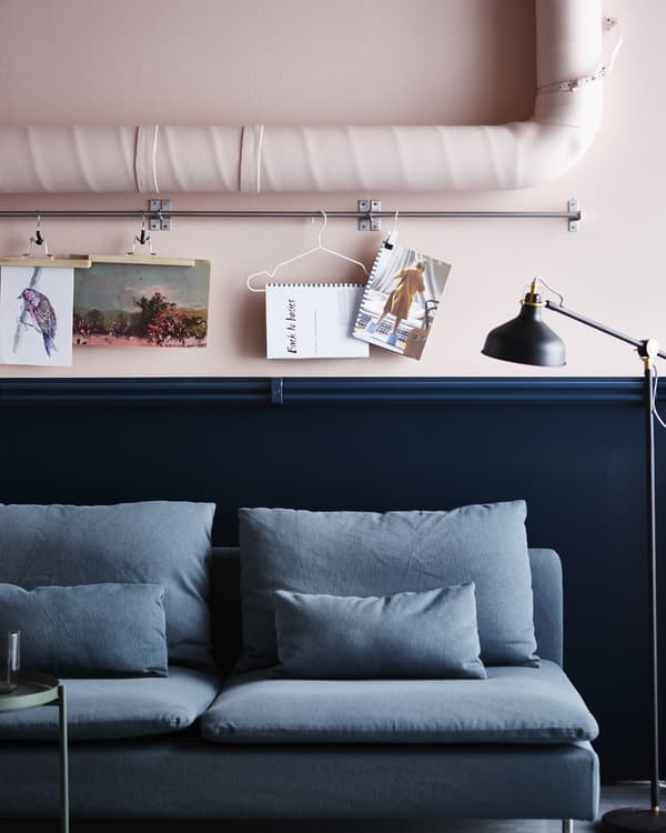Artwork and a calendar are hung with hanger from a rail mounted between pipes.