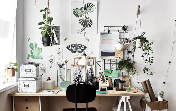 Artwork and inspiration displayed on a wall above a wooden desk and black chair.