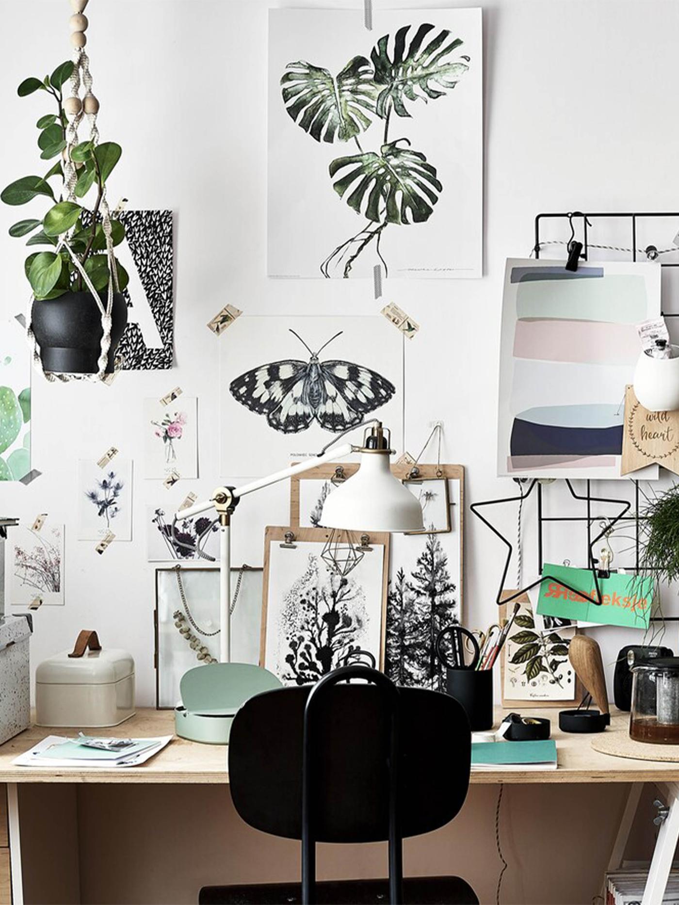 Artwork and inspiration displayed on a wall above a wooden desk and black chair.