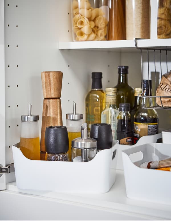 As caixas de plástico liso IKEA VARIERA en branco, con asas doadas de agarrar, son solucións para evitar os derramos das botellas altas de aceite e salsas.