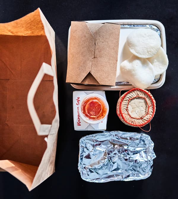 Asian takeaway containers are shot from above on a black surface.
