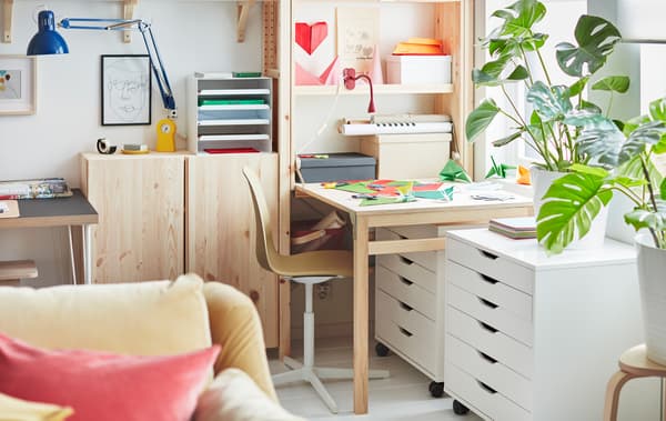 Au bout d’une unité de rangement IVAR occupant toute la largeur d’un mur, un espace de travail créé avec une table dépliée est couvert de papier coloré.