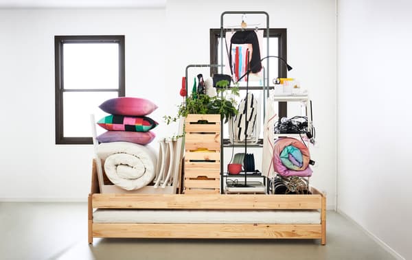Au centre d’une pièce, un lit et tous les articles et meubles essentiels pour s’installer dans un petit appartement.