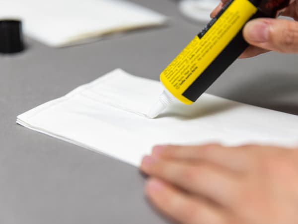 Auf die Papiertüten wird Kleber in einer T Form aufgetragen. Die Tüten werden zusammengeklebt.