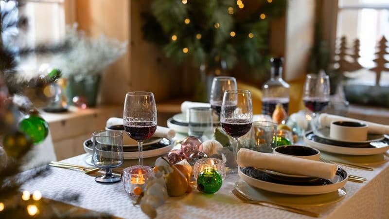 Auf einem festlichgedeckten Tisch befindet sich STRIMMIG und OMBONAD Essgeschirr und im Hintergrund sieht man verschwommen einen Christbaum.