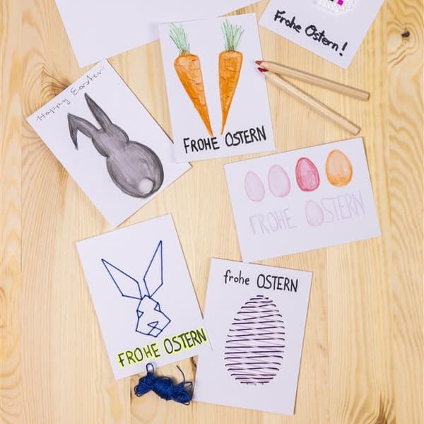 Auf einem Holztisch liegen Bilder von einem Osterhasen und Karotten