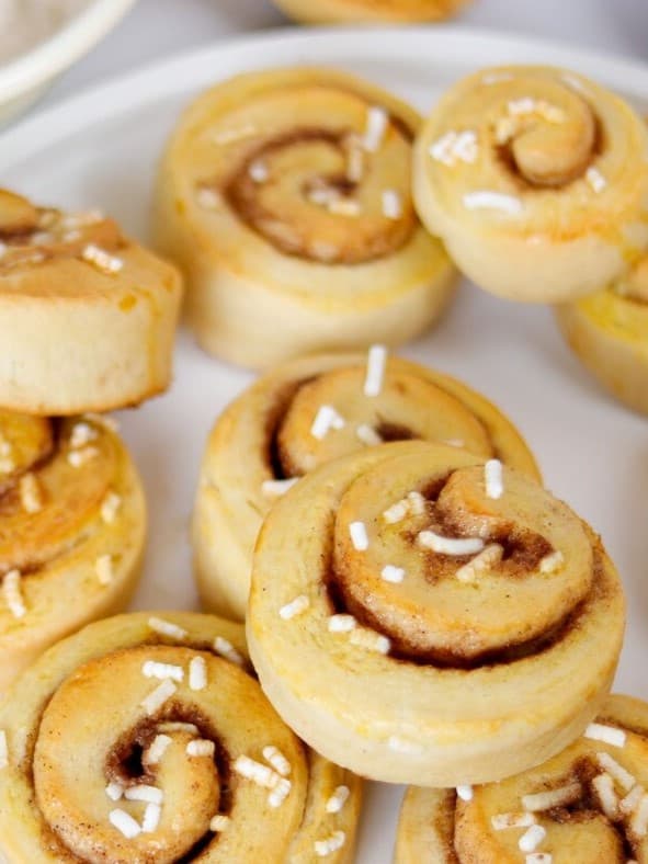 Auf einem Tablett liegen viele Zimtschnecken mit Zucker darauf.