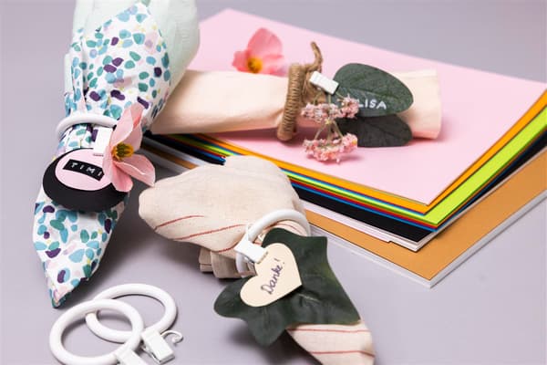 Auf einem Tisch liegen bunte Zettel und Servietten mit den selbstgebastelten Serviettenringen.
