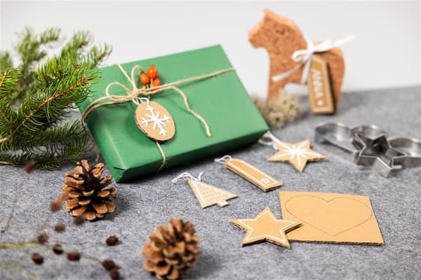 Auf einem Tisch liegt ein grünes Geschenk und selbstgemachte Anhänger.