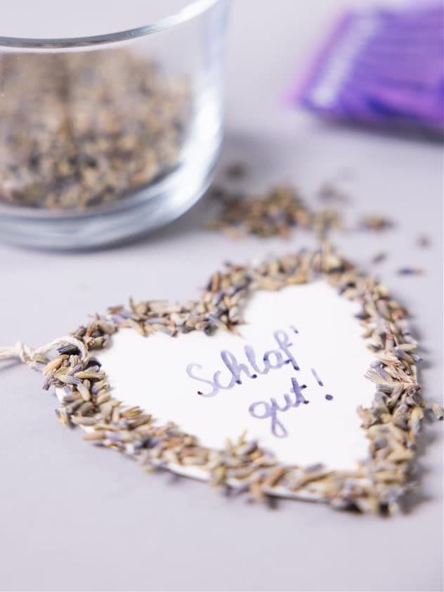 Auf einem Tisch liegt ein Herz mit einer Schrift und außen rum sind kleine Steine drauf geklebt