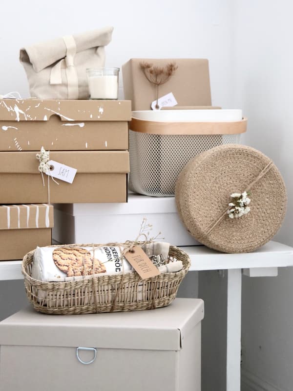 Auf einem Tisch stehen verschiedene Geschenkverpackungen in Beigetönen. Der Link führt zu Geschenkideen