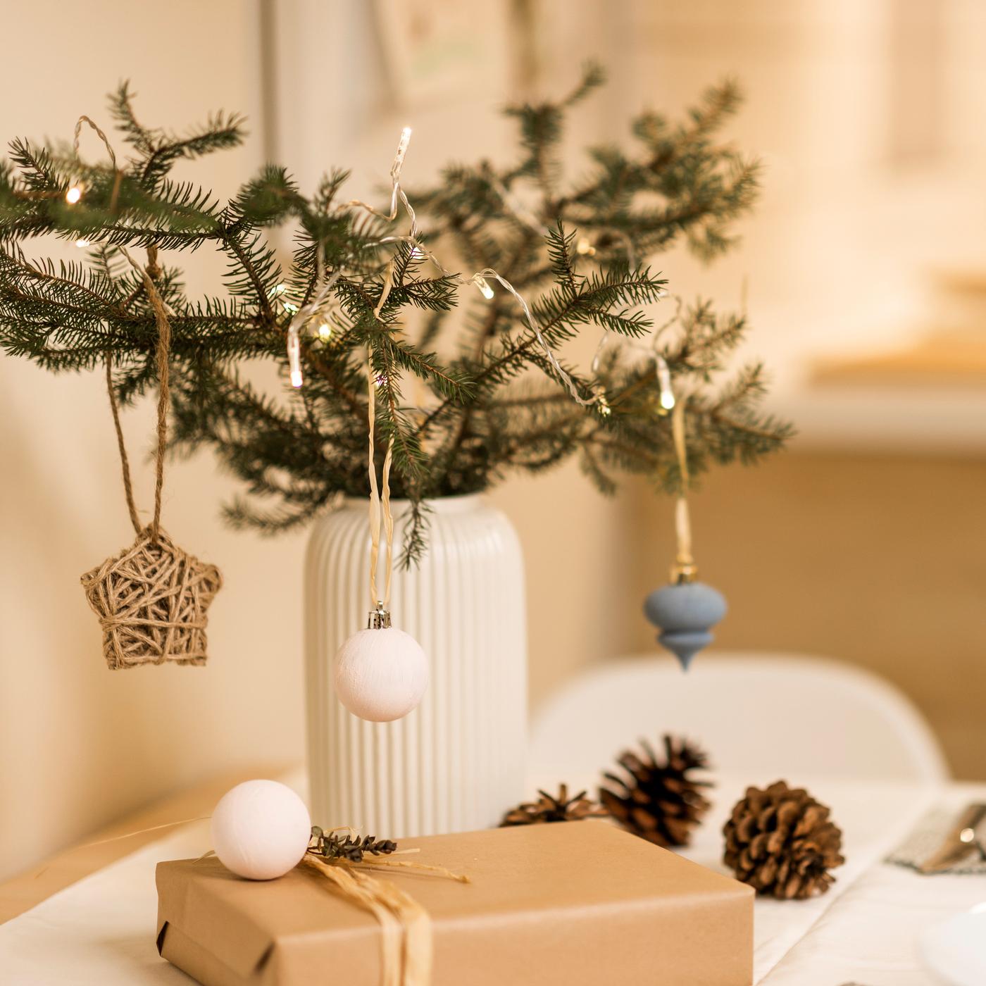 Auf einem weißen tisch steht eine grüne Pflanze und an der Pflanze hängt Deko.