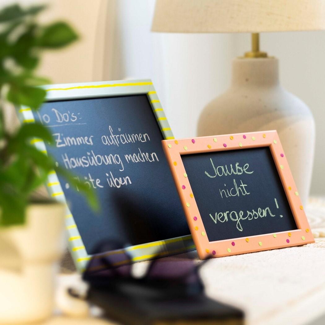 Auf einem weißen Tisch steht eine Tafel mit einer Schrift darauf und daneben eine Tischlampe.