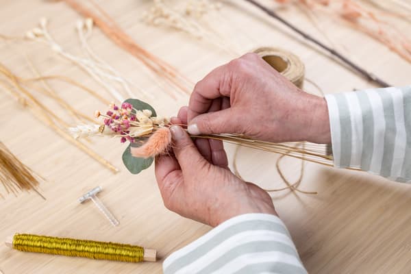 Aus den verschiedenen Blumen binden Hände ein kleines Sträußchen.