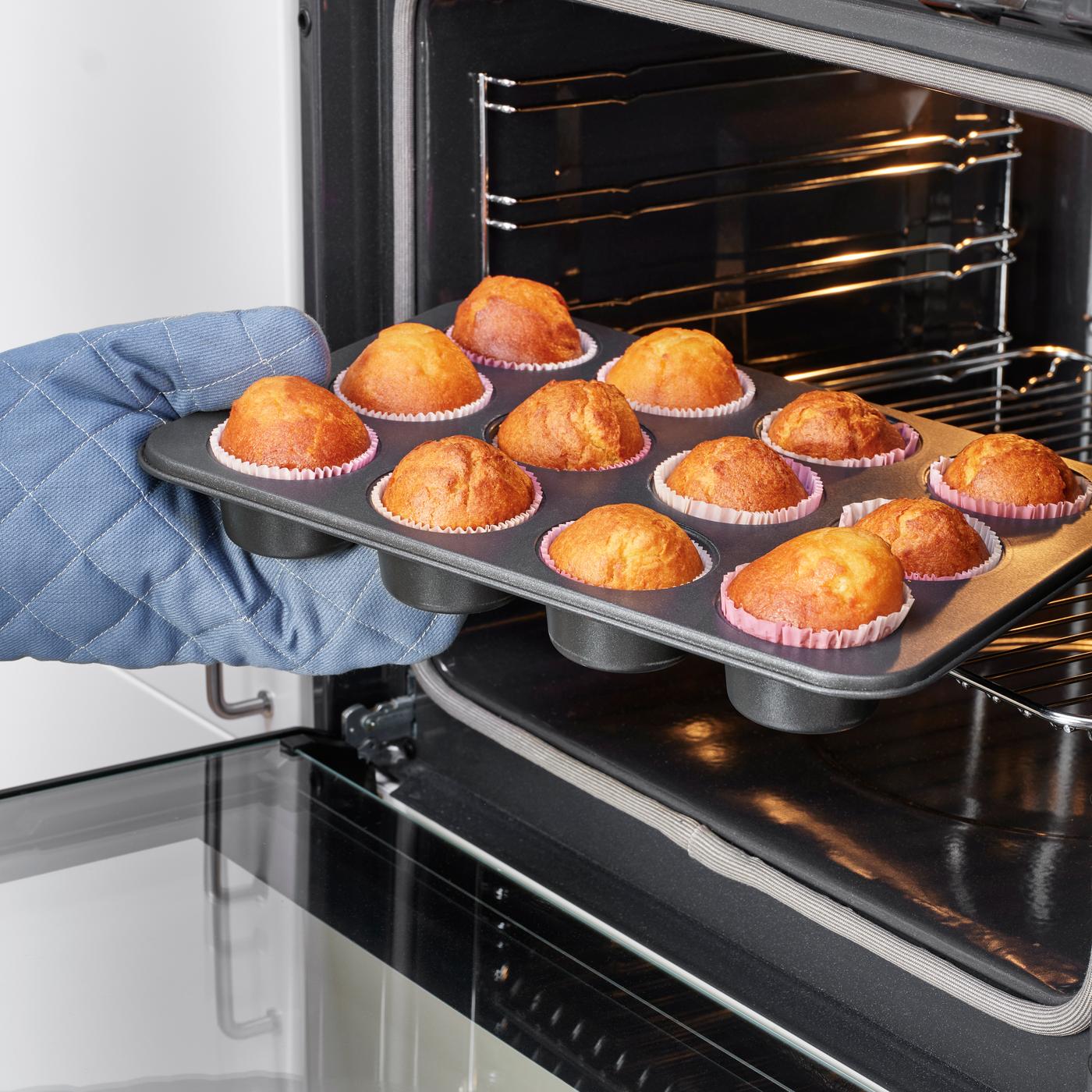 Aus einem Backofen wird ein Blech goldgelb gebackene Muffins entnommen.