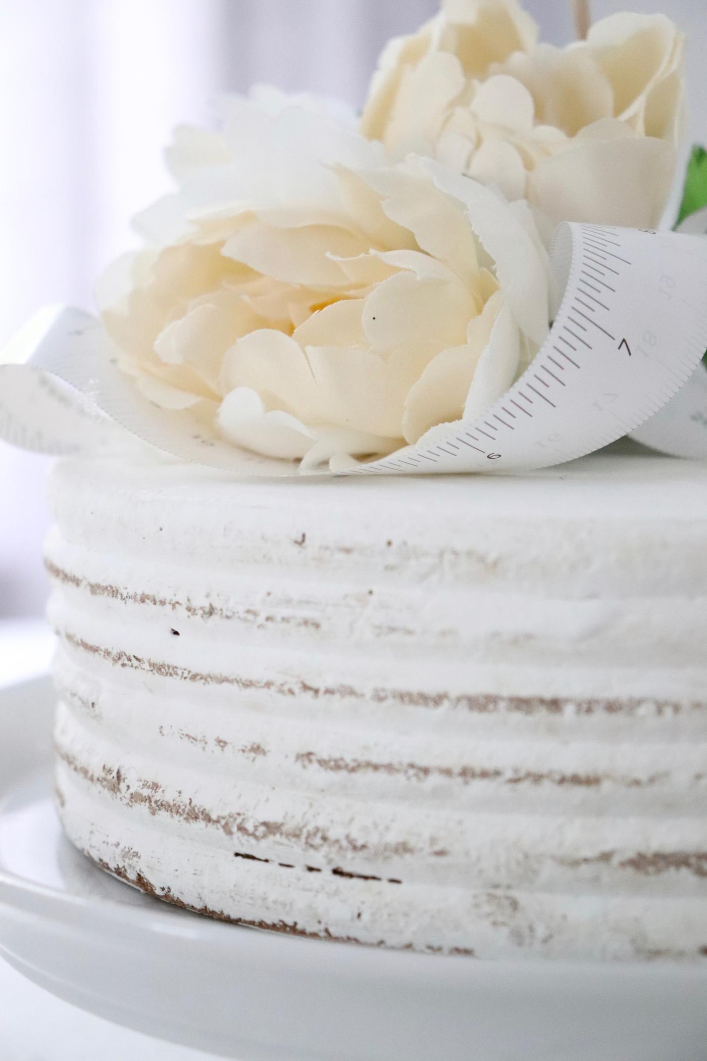 Ausschnitt einer weißen Torte mit Blumendeko.