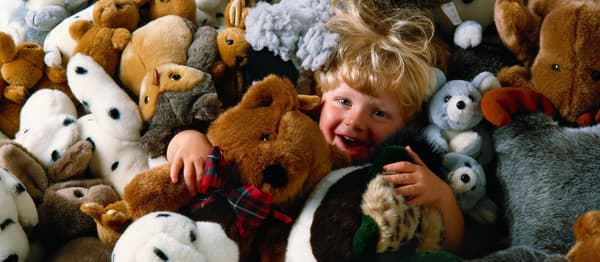 Baby boy playing among soft toys.