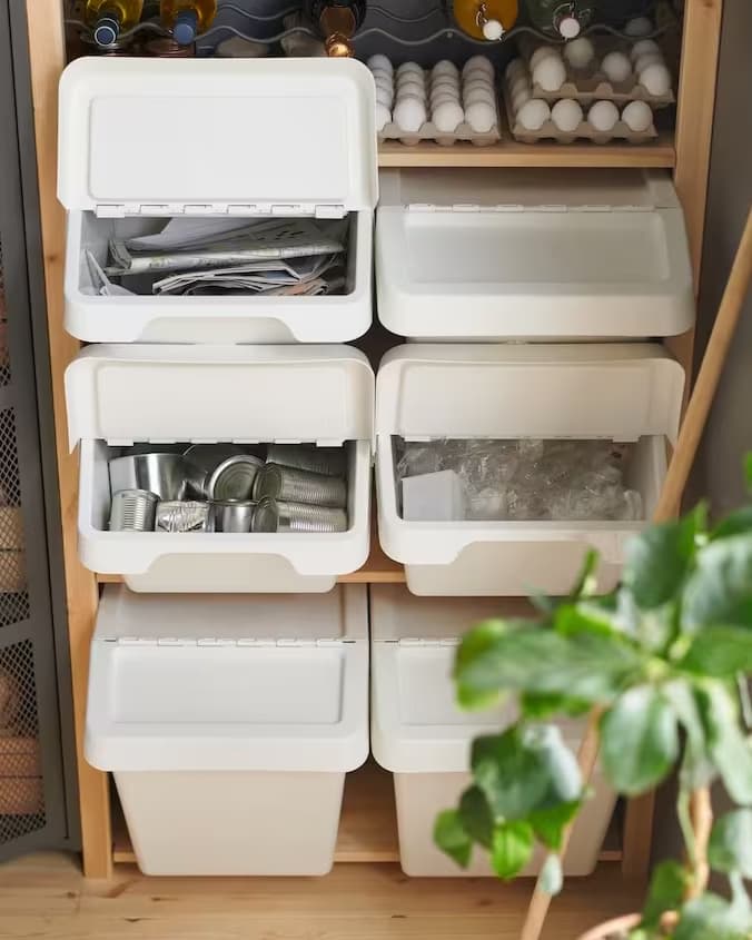 Bacs de rangement blancs ouverts contenant bocaux, œufs et bouteilles, organisés sur une étagère en bois.