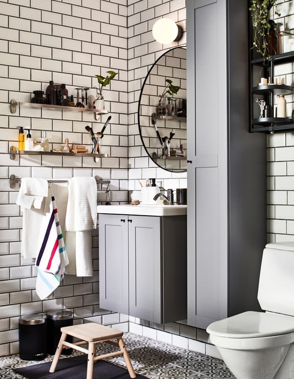 Bagno con mobili ENHET grigi e mensole in vetro BROGRUND sulla parete, una per lui e una per lei.
