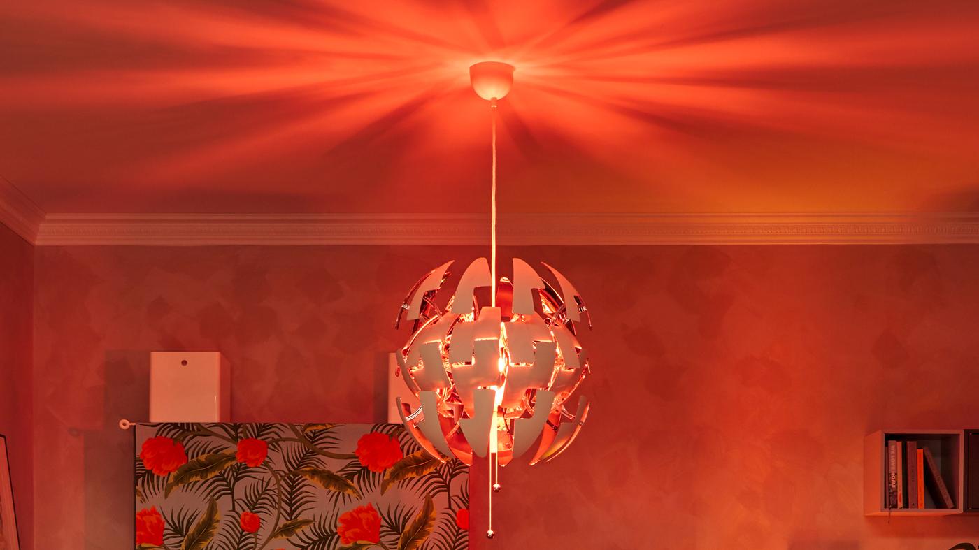 Bahagian atas ruang tamu, dipenuhi dengan lampu pendan IKEA PS melantun kemerah-merahan, menyinari siling.