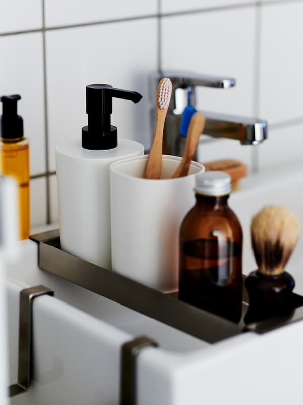 Bahagian dalam bilik mandi berjubin putih dengan rak nipis diletakkan merentasi sink cuci tangan LILLÅNGEN, mengandungi set bilik mandi STORAVAN.