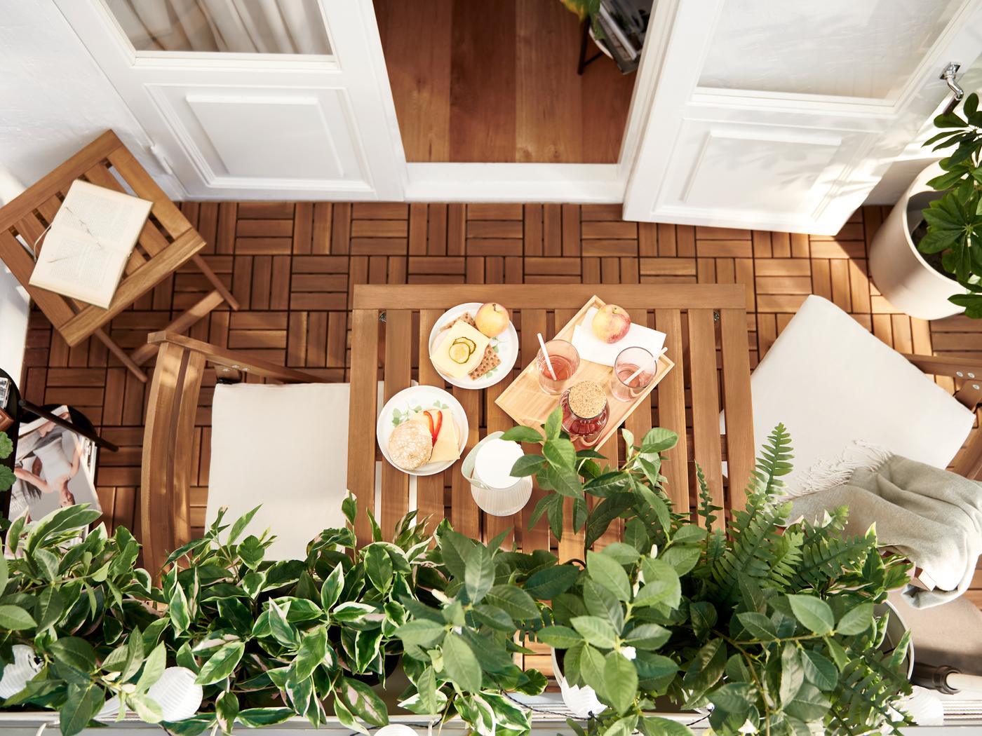 Balcon avec mobilier NÄMMARÖ et caillebotis RUNNEN en lattes d’acacia, et plantes vertes artificielles FEJKA.