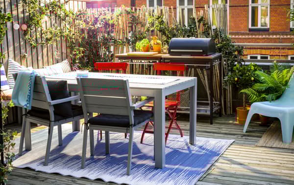  Balcon avec table et chaises, banc, barbecue et grand nombre de plantes vertes.