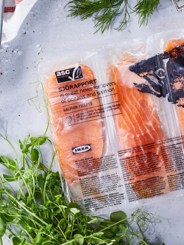 Balenie lososových filetov SJÖRAPPORT je položené na pracovnej ploche vedľa zväzku byliniek.
