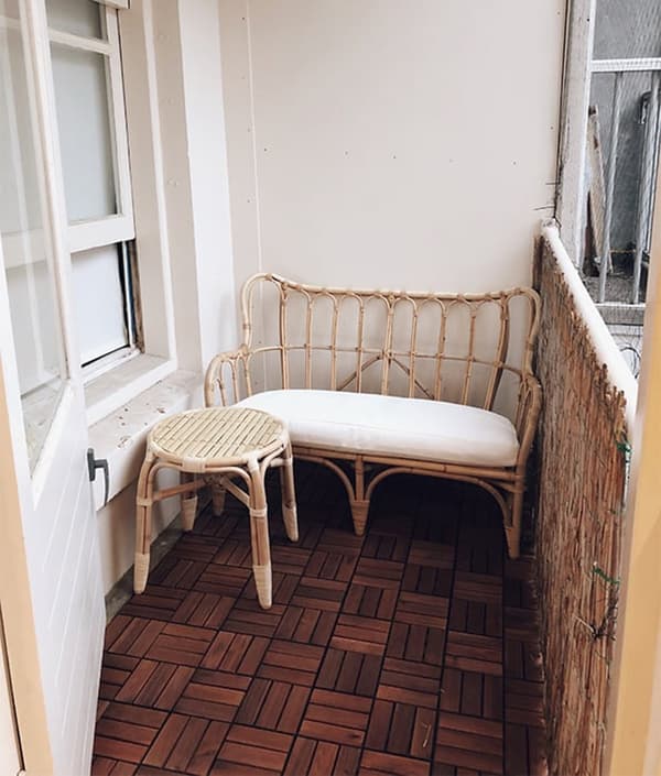 Balkon met houtgekleurde tegels waarop meubels staan.