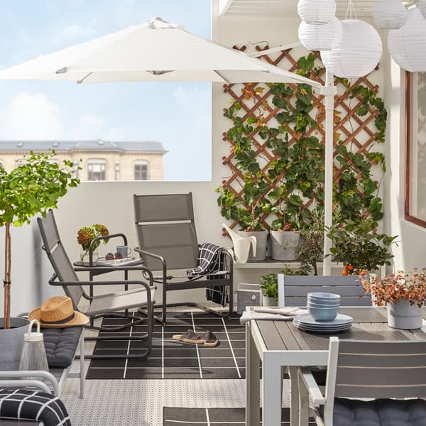 Balkon s křesly a stolkem HUSARÖ, bílým stolem, šedými židlemi a šedo-bílými koberci.