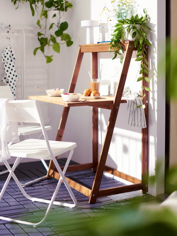 Balkon se skládacím stolem DJUPÖN a bílými skládacími židlemi GUNDE.