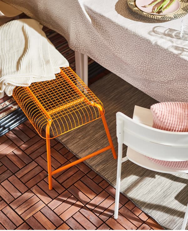 Banc IKEA VÄSTERÖN orange à côté d’une table.