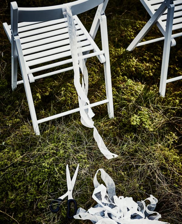Bandelette découpée dans un filet SOLIG et nouée au dos d’une chaise pliante blanche 