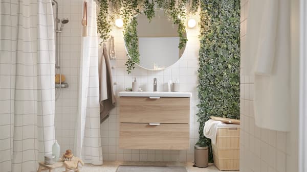 Baño con muebles GODMORGON. Hay toallas azules en ambos costados y una planta en la ventana.