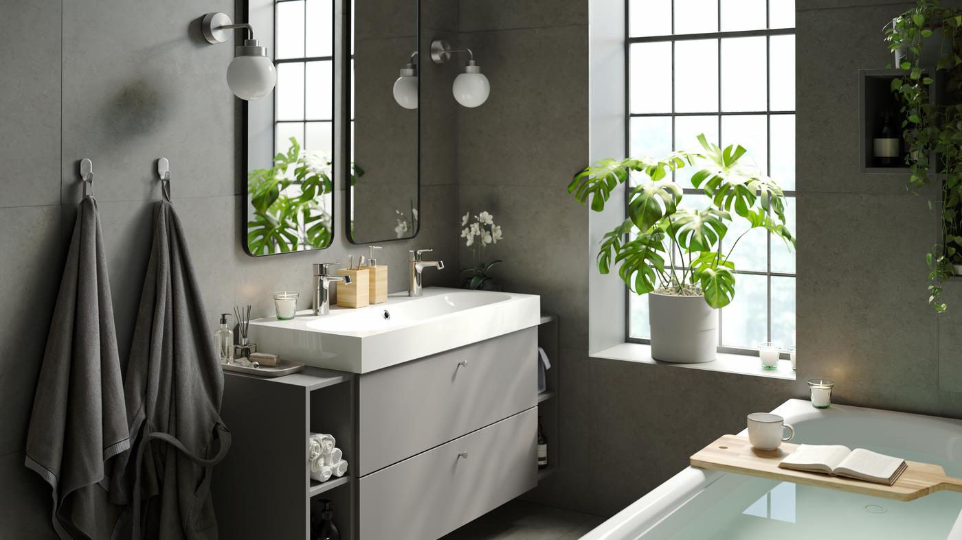 Baño tranquilo y relajante con una elegante y moderna tina, un amplio lavabo doble con almacenamiento, espejos dobles y plantas verdes de interior.