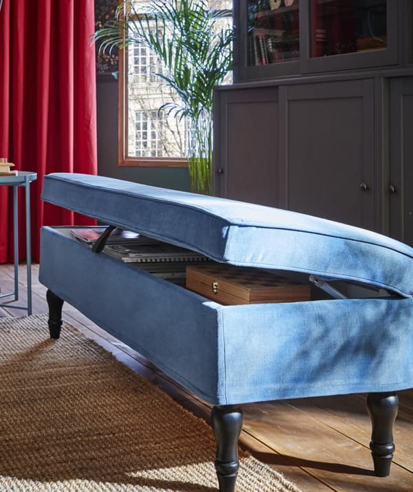 Banquette bleu clair avec couvercle partiellement ouvert révélant les choses rangées à l’intérieur.