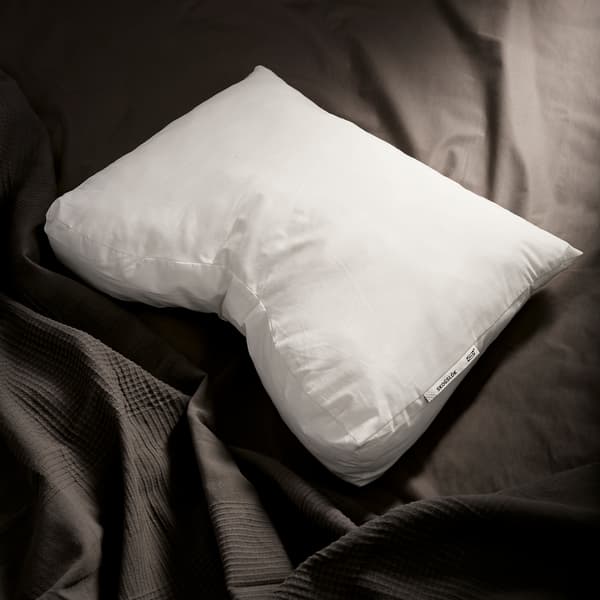Bantal ergonomik SKOGSLÖK IKEA yang gebu, ditunjukkan berlatarbelakangkan linen katil berwarna kelabu gelap.