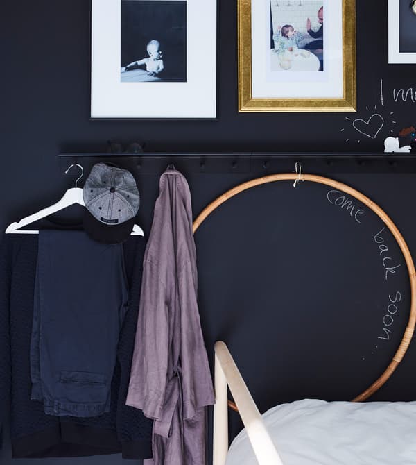 Barre de support murale avec crochets et tenue du lendemain préparée sur un cintre.