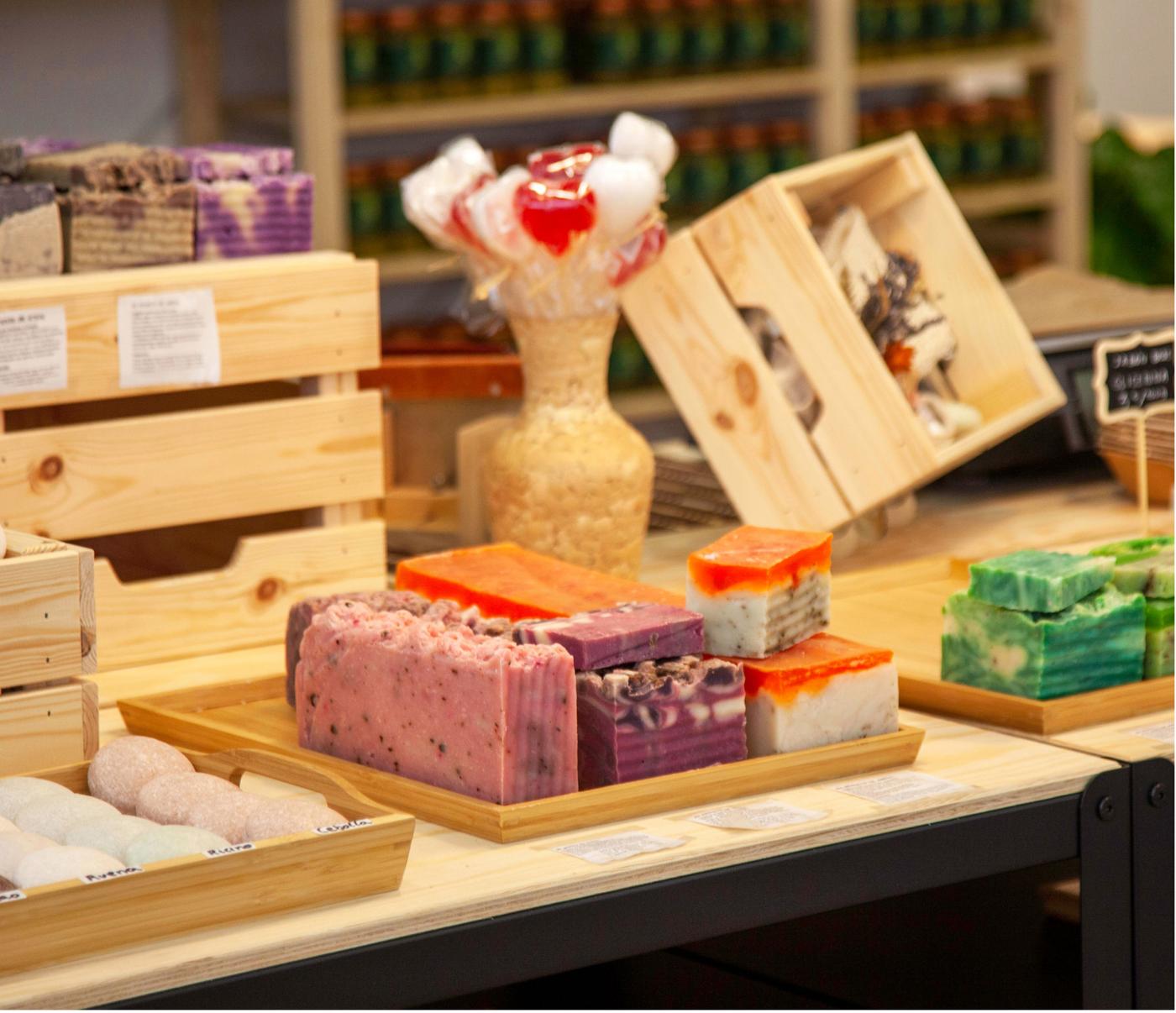 Barres de sabó de colors variats exposades en safates de fusta en una botiga de productes naturals.