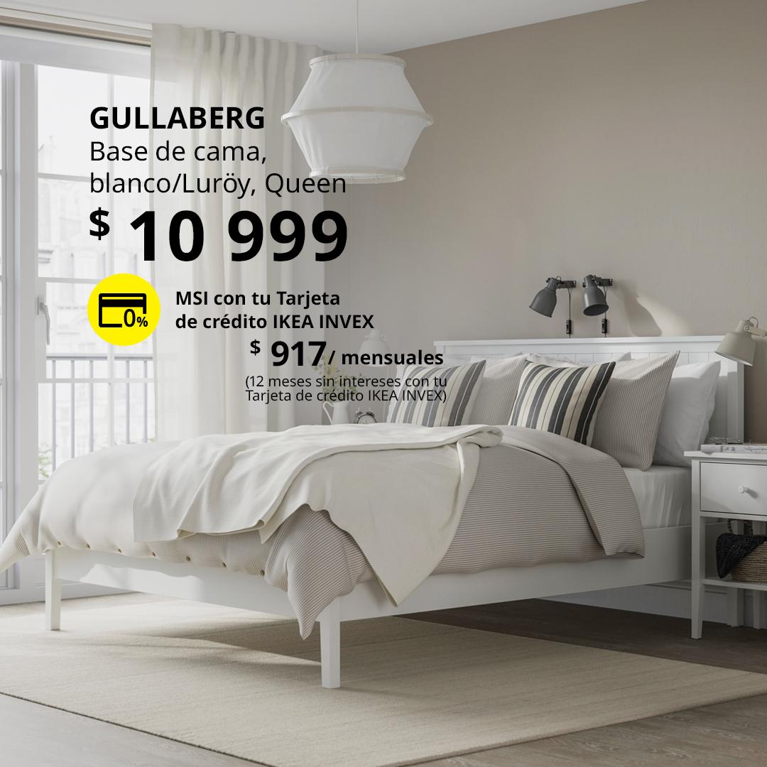 Base de cama GULLABERG blanca en un dormitorio con ropa de cama en tonos blanco y beige, acompañada de mesas de noche y lámparas de pared.