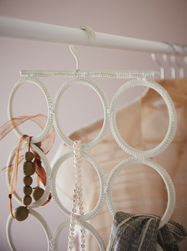 Bastone appendiabiti in un guardaroba e appenditutto KOMPLEMENT con collane, un foulard e altri accessori.