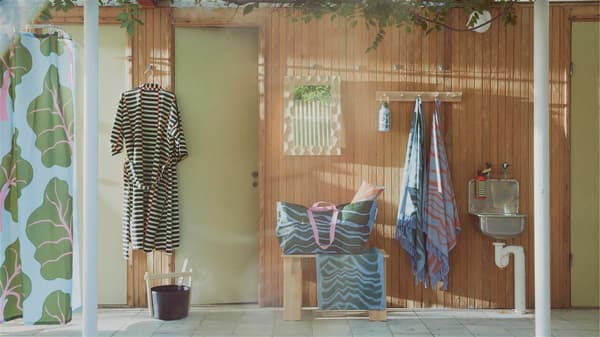 BASTUA collection including a robe, bag, towel shower curtain and water bottle is displayed in a sauna setting.