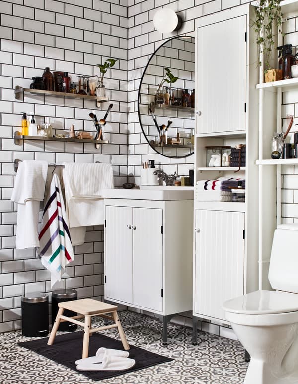 Bathroom with white SILVERÅN washstand and cabinets, and wall-mounted BROGRUND glass shelves: one for him and one for her.