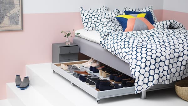Bed met daaronder een uitschuifbaar rek waarop schoenen staan.