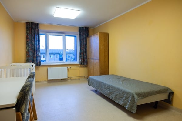 Bedroom before interior renovation with a bed and yellow walls.