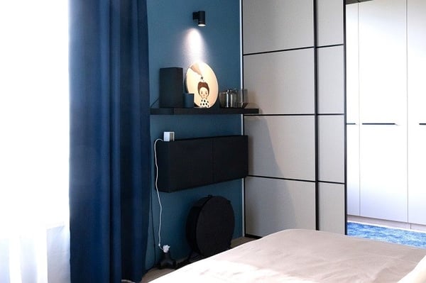 Bedroom corner with blue accent wall, floating cabinet, and soft natural light