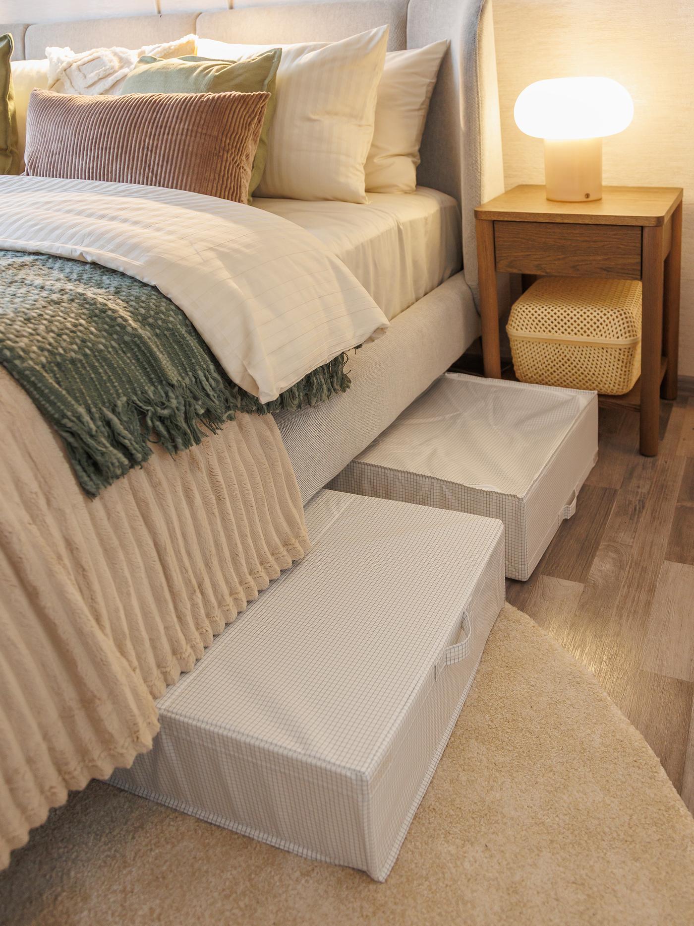 Bedroom featuring underbed storage boxes pulled out beneath the neatly made bed with layered bedding.