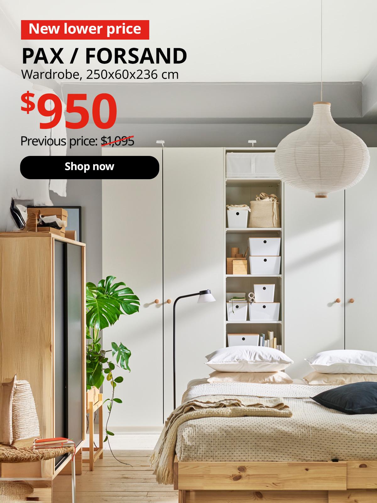 Bedroom in beige and white with bed in natural wood and beige bedding. A combination of white PAX wardrobes in back. A red tag with white text that reads "New lower price". Black text overlay image that reads "PAX / FORSAND, Wardrobe, 250x60x236 cm, Previous price $1,095". New lower price in red overlay image reading "$950". 