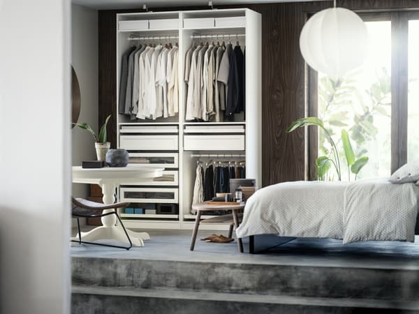 Bedroom space with an open wardrobe and white duvet covers on the bed